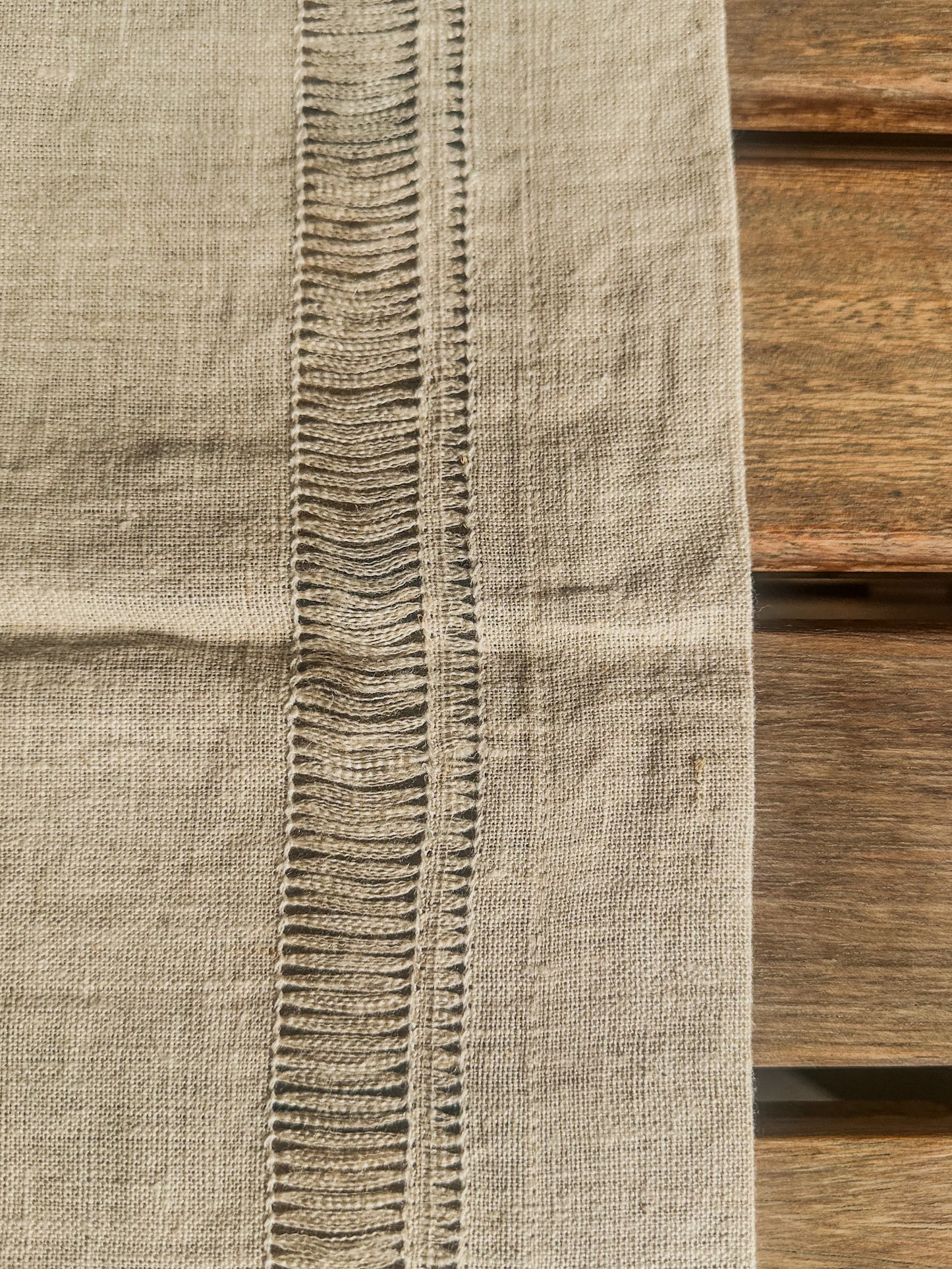Close-up of a textured beige handmade table runner with a wooden background