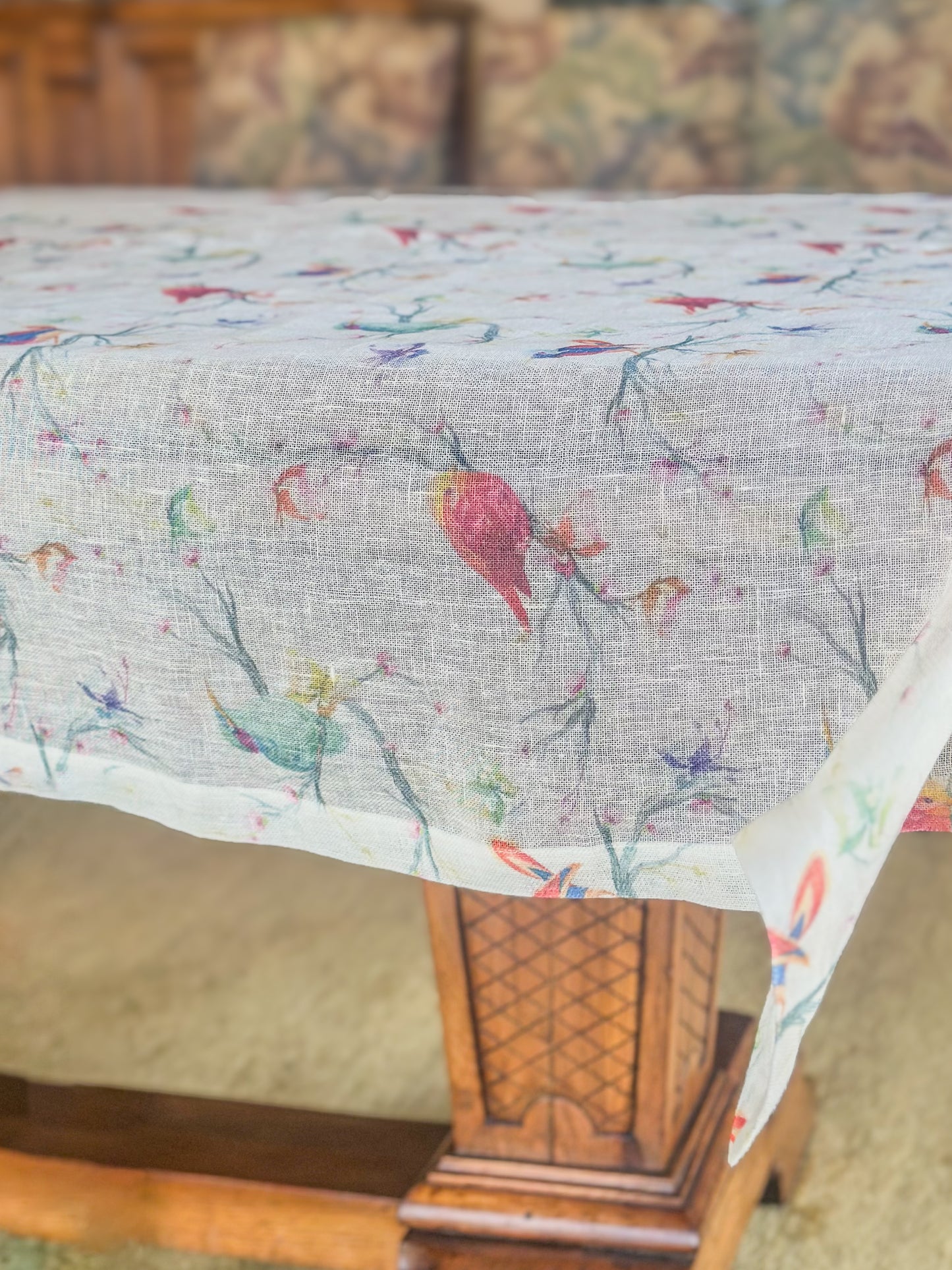 Egyptian linen tablecloth with colorful bird pattern on a wooden table with chairs in the background