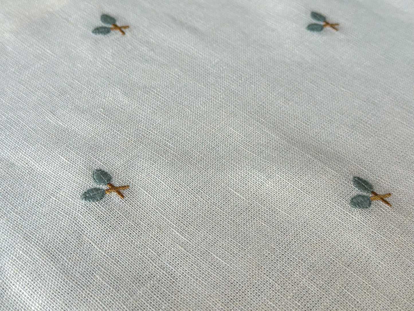 Textured linen placemat with small embroidered designs on a light background