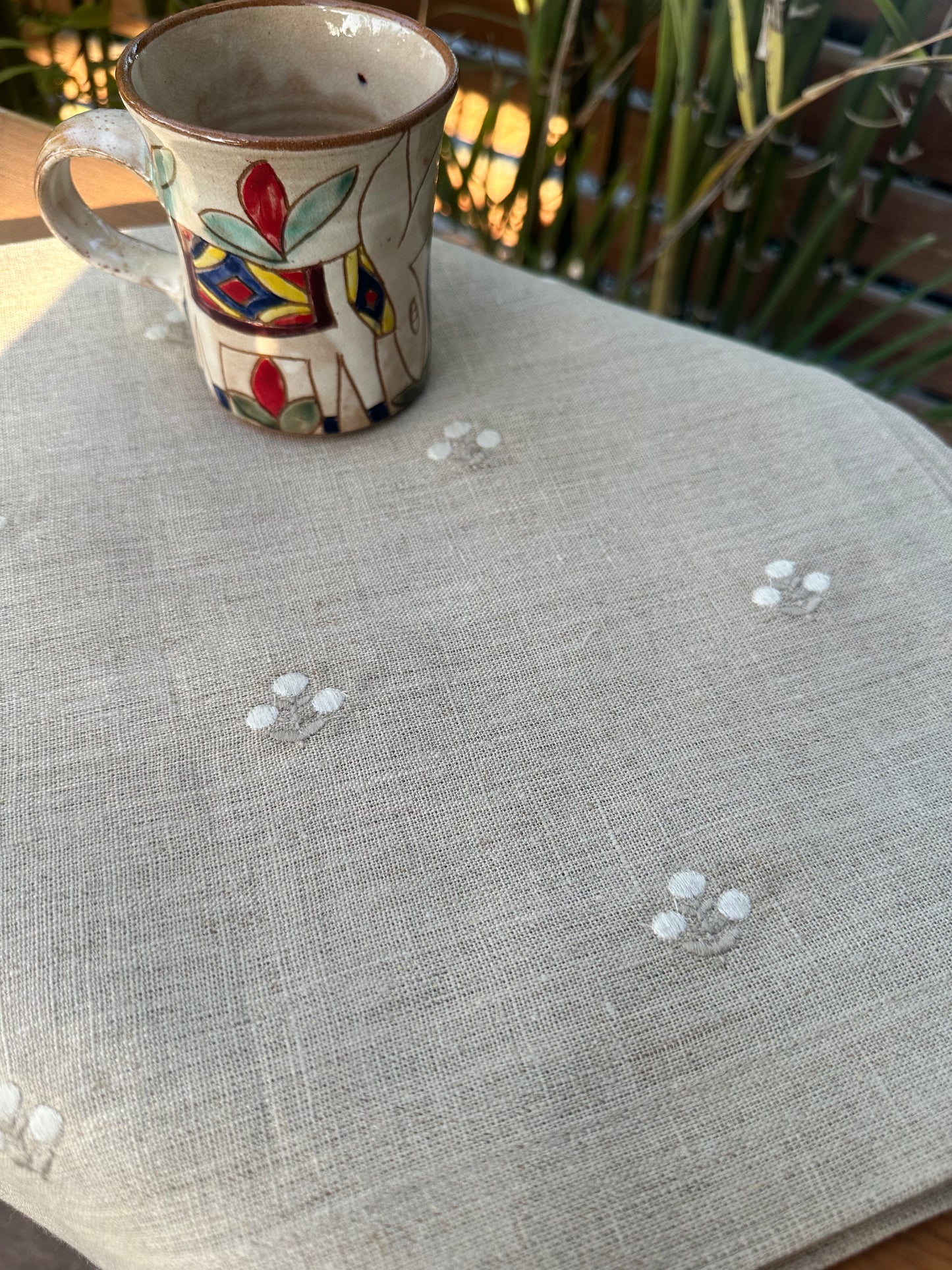 Decorative mug on a linen runner with minimal floral embroidery.
