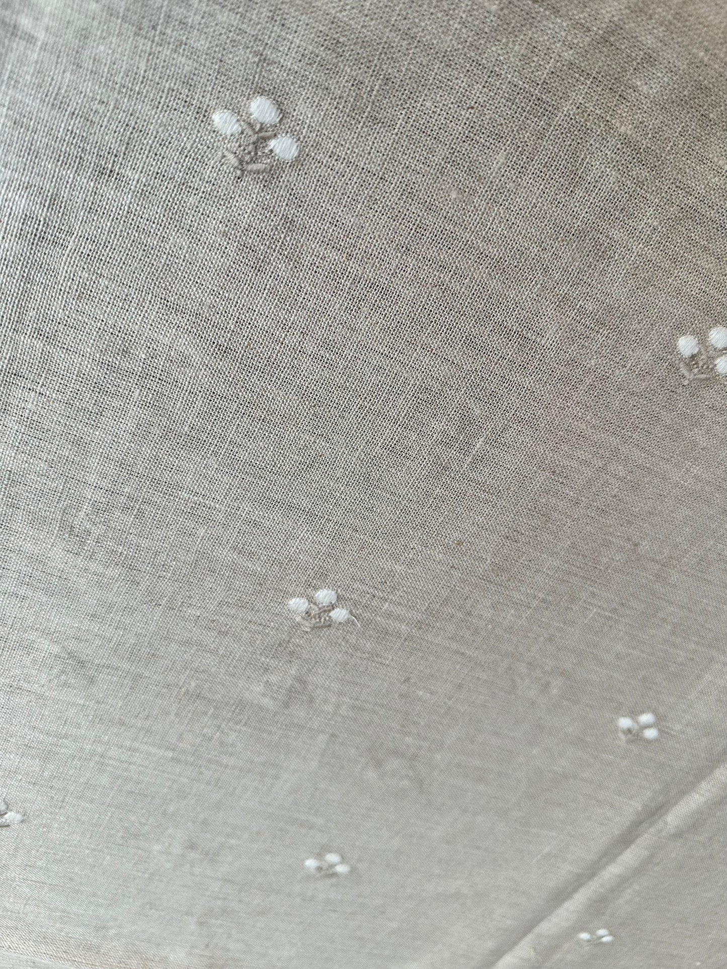 Close-up of beige linen fabric with small white floral patterns