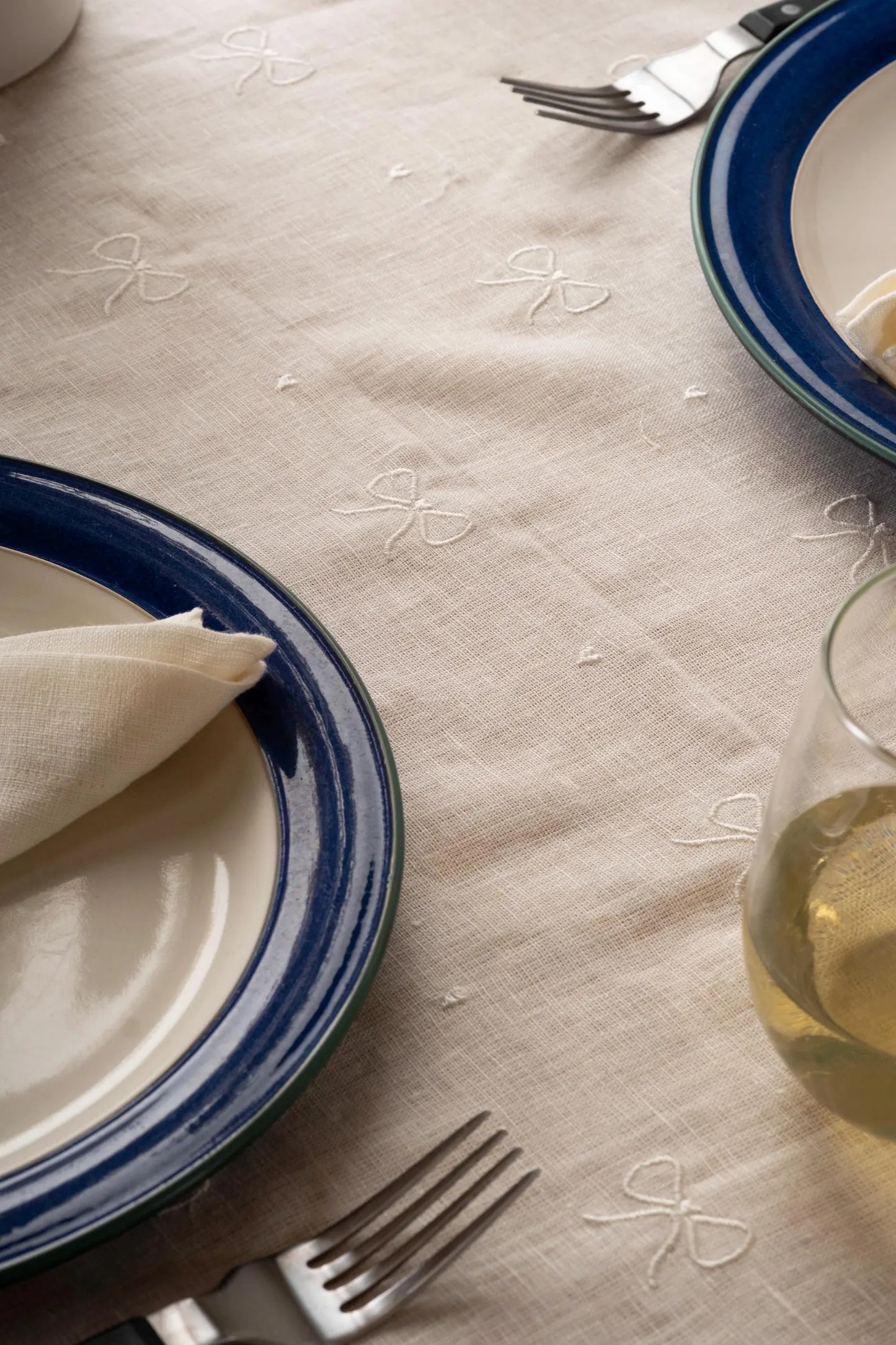 Off white linen tablecloth with subtle ribbon embroidery.