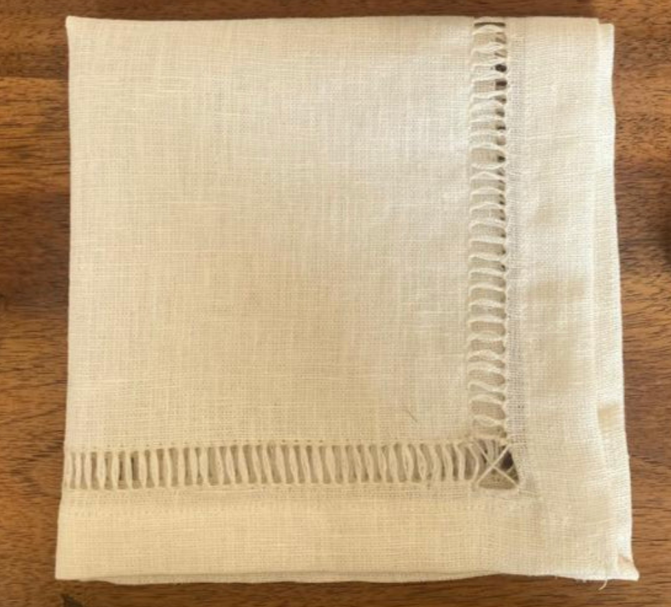 Handmade Egyptian linen off-white napkin with fringe on a wooden surface