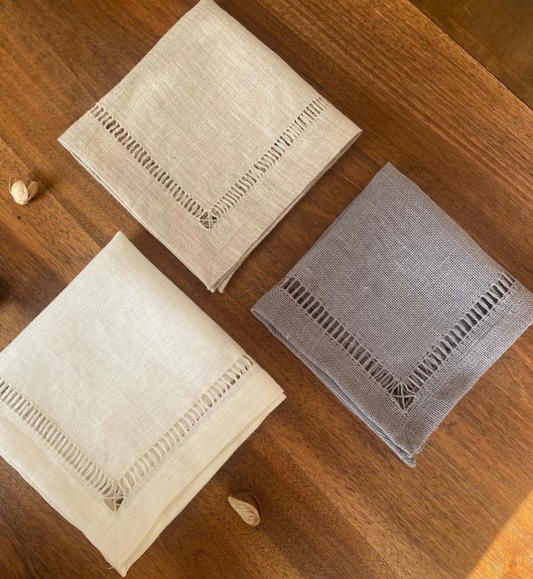 Two beige and one gray handmade Egyptian linen napkins on a wooden surface