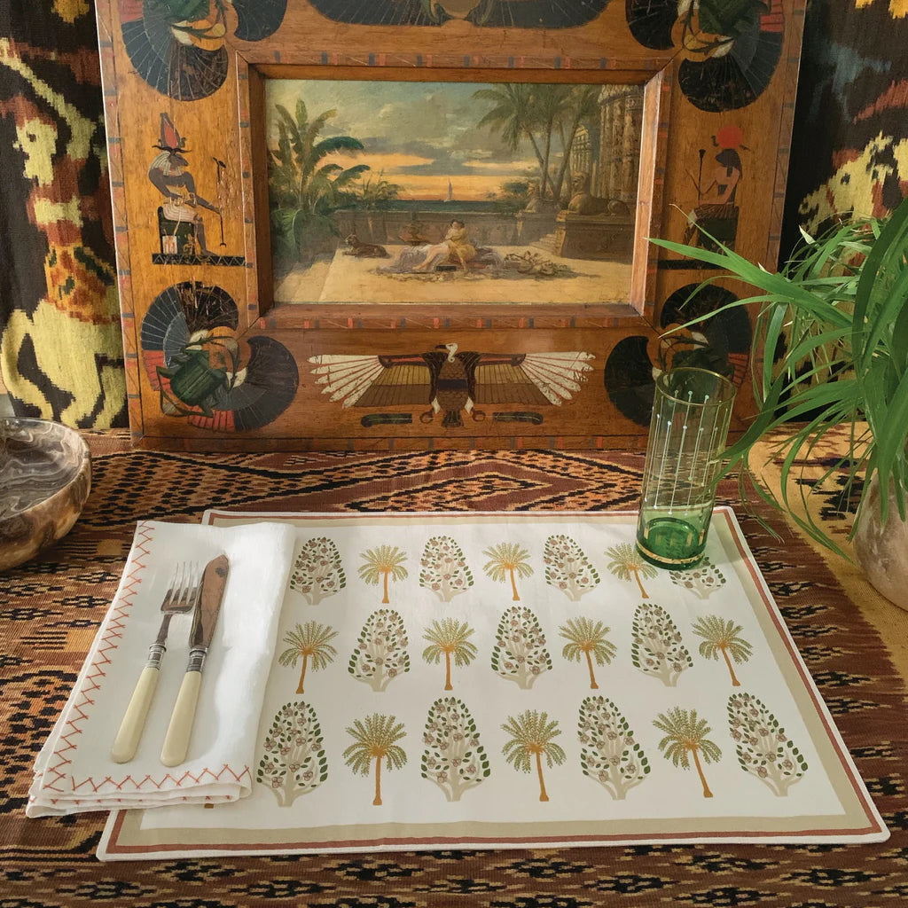 Decorative table setting with a patterned placemat, cutlery, and a framed painting on a textured surface.