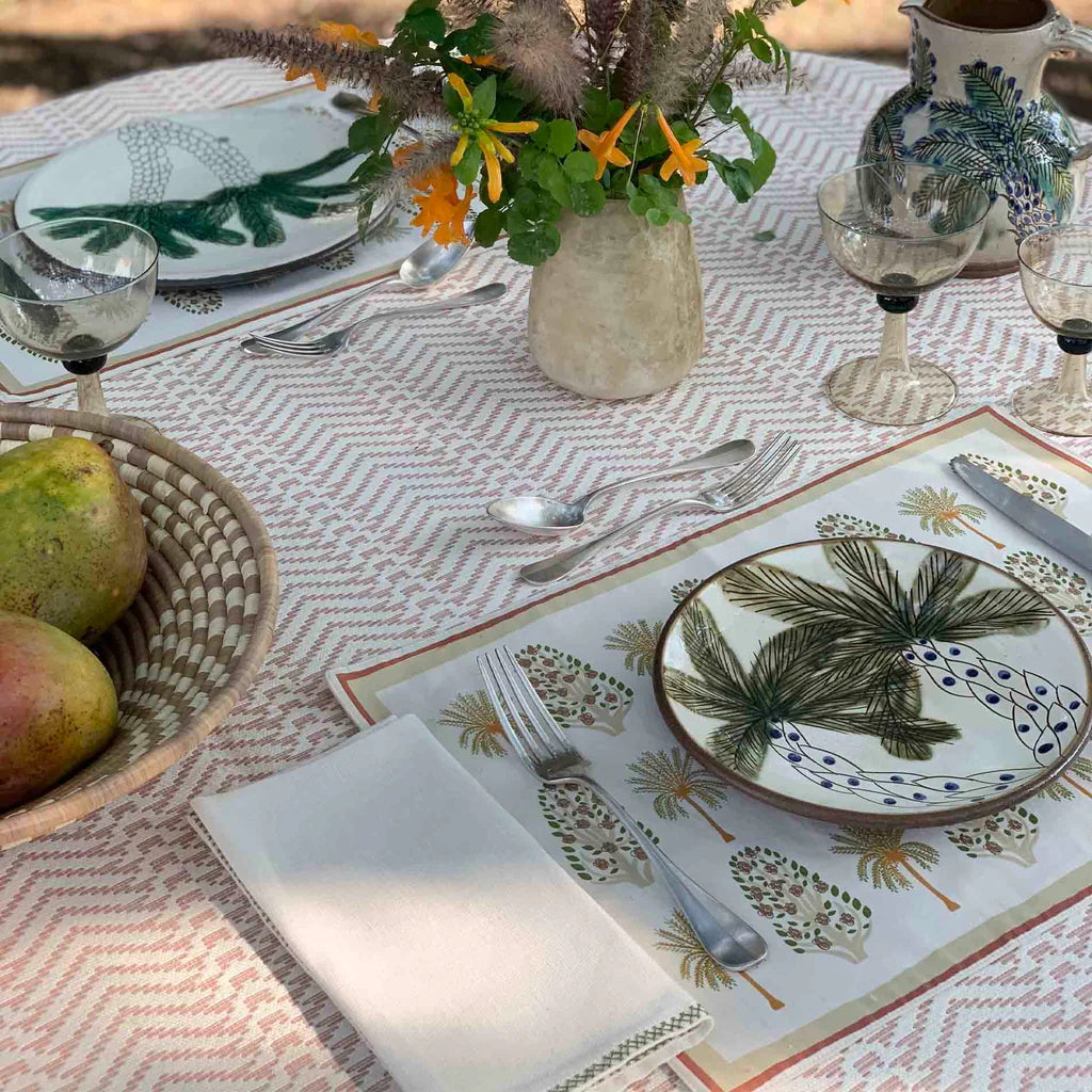 Decorative table setting with palm tree-themed plates and a patterned tablecloth.