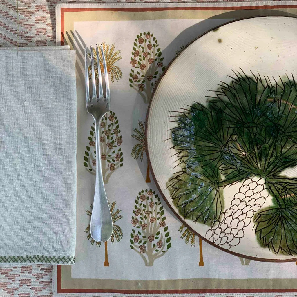 Plated dish with green leaf design on a decorative tablecloth with floral patterns.